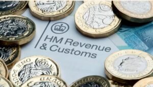 Stack of UK £1 coins placed on top of an HMRC tax document